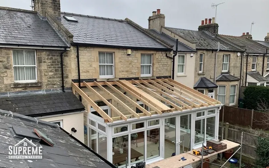 New timber roof frame being built over a white uPVC conservatory