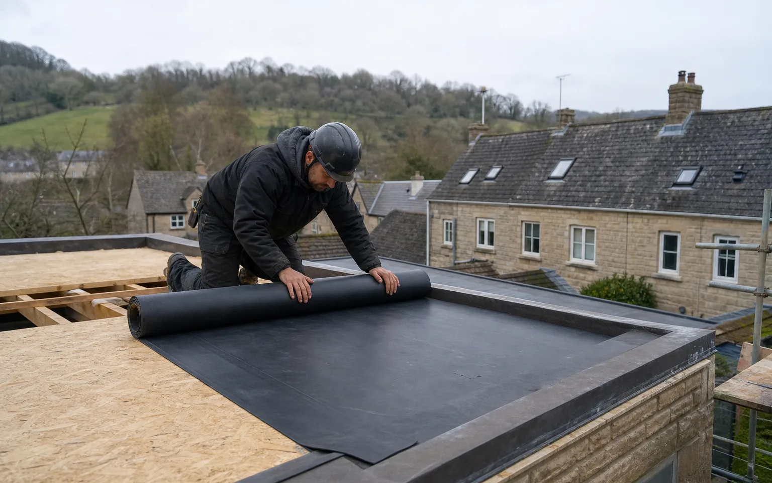 Roofer rolling out black rubber membrane over a flat roof deck