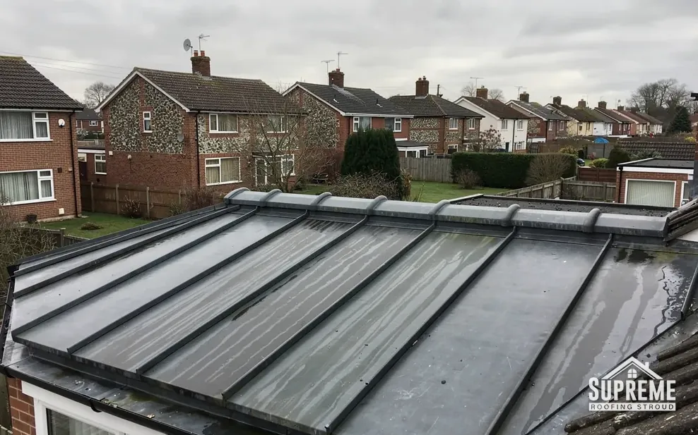 Low-pitched ribbed metal roof on a single-storey building beside brick houses