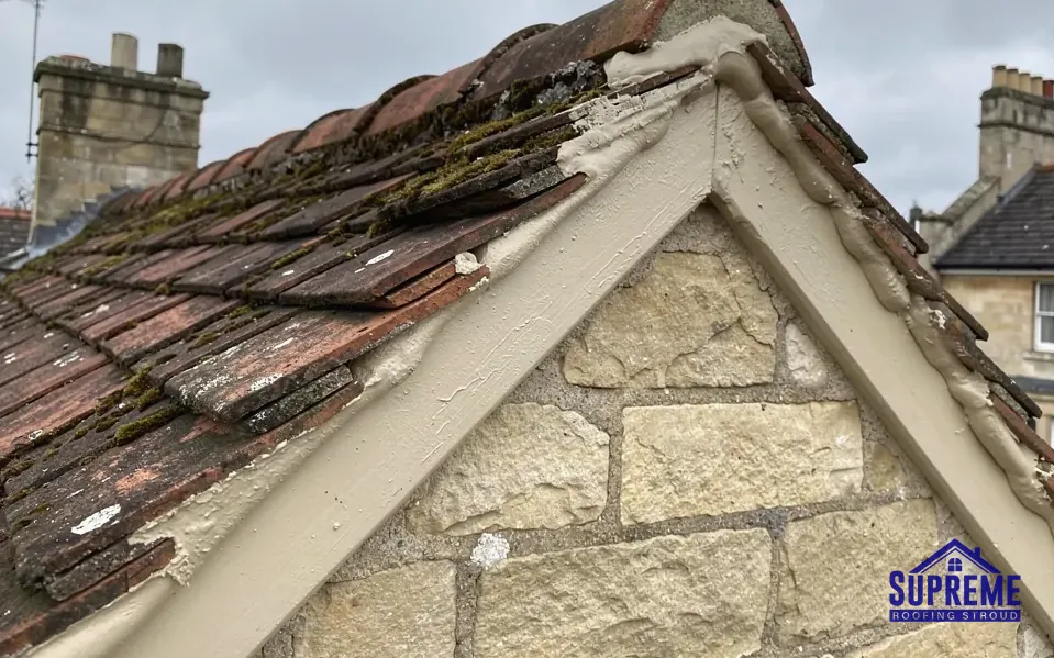 Stone gable end with a mossy clay tile roof and verge