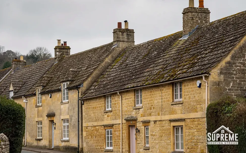 Stone cottages with steep moss-covered stone tile roofs and brick chimneys