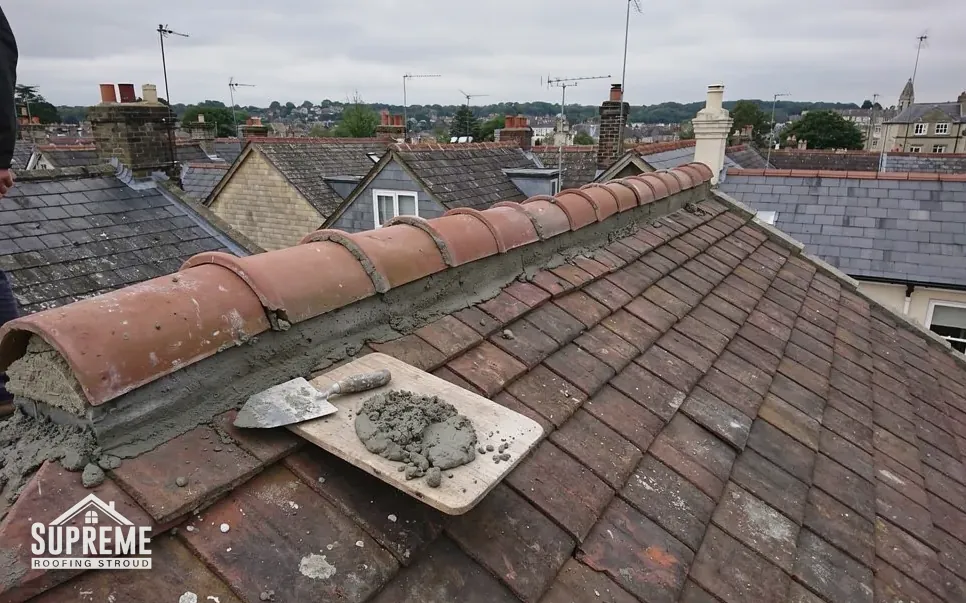 Roofer fixing a dry ridge system along the top of a tiled roof