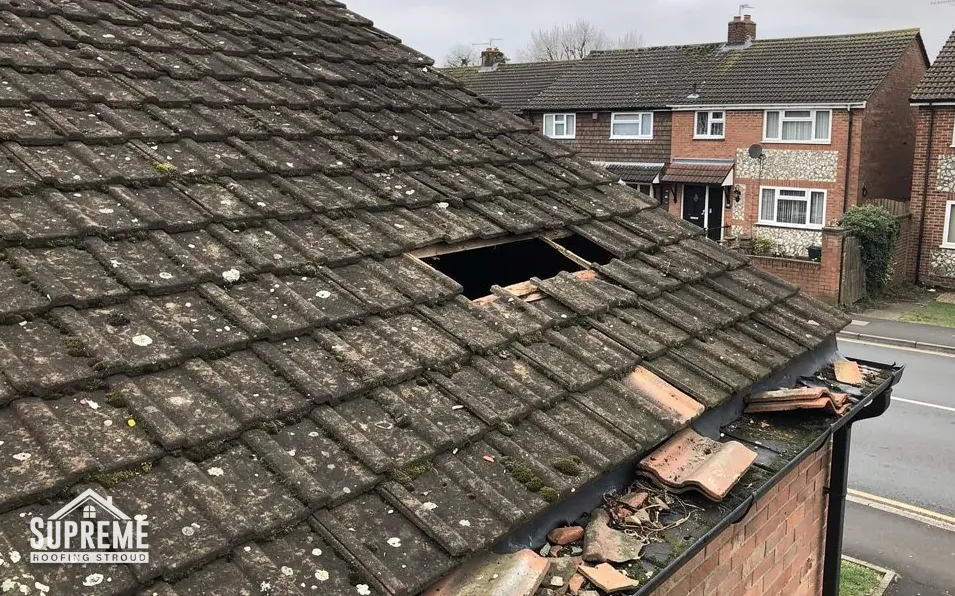 Concrete tile roof with broken tiles and a hole near the eaves