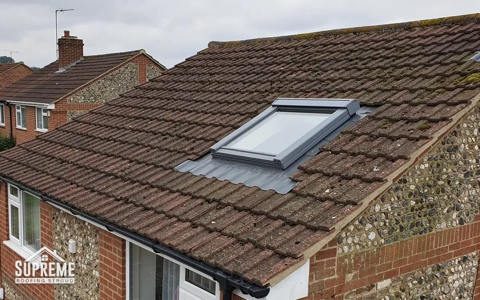 Roofer fitting a roof window into a tiled pitched roof above a loft room in Stroud
