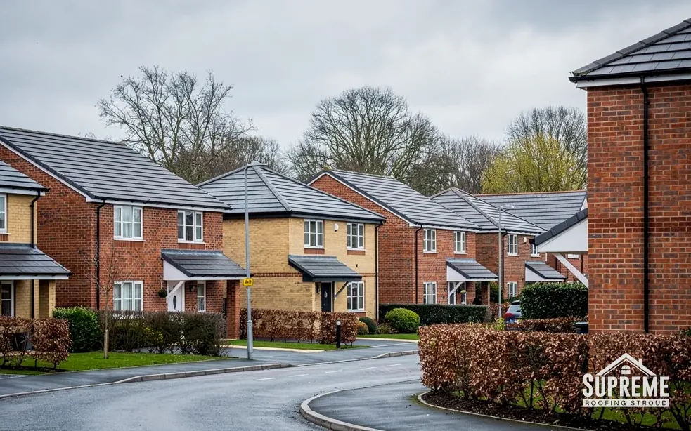 Modern brick housing estate with grey tiled roofs along a curving road