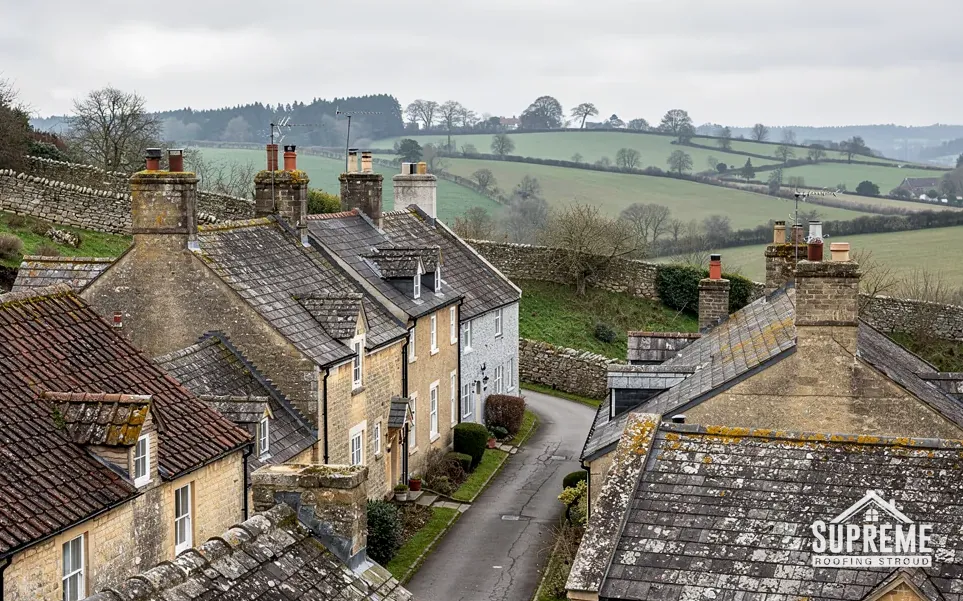 Stone village houses with slate and tile roofs above green fields